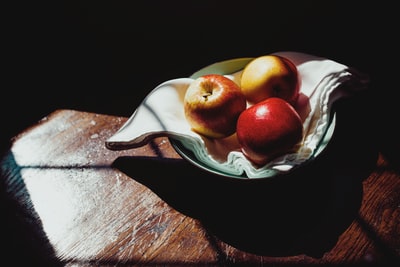 红色苹果白色和绿色植物的陶瓷碗
